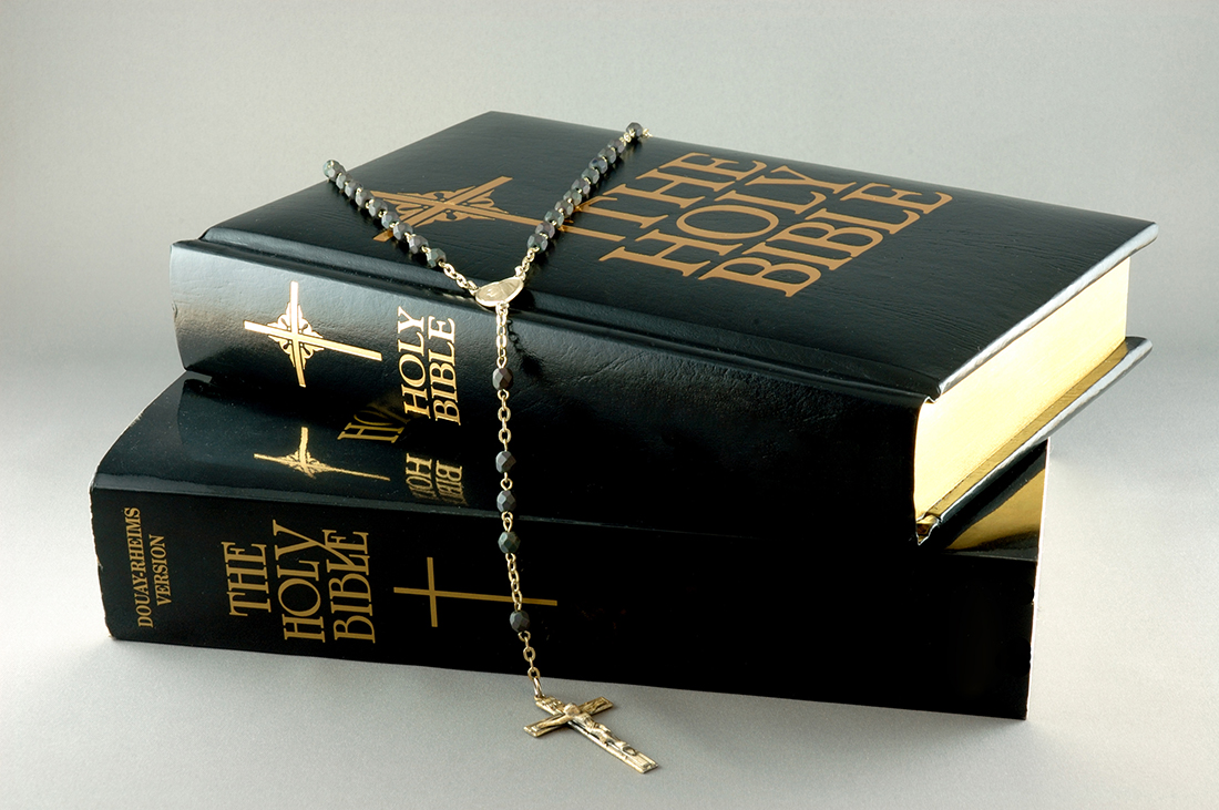 Two Bibles and a rosary, embodying the essence of preaching and teaching ministry in the Christian faith.